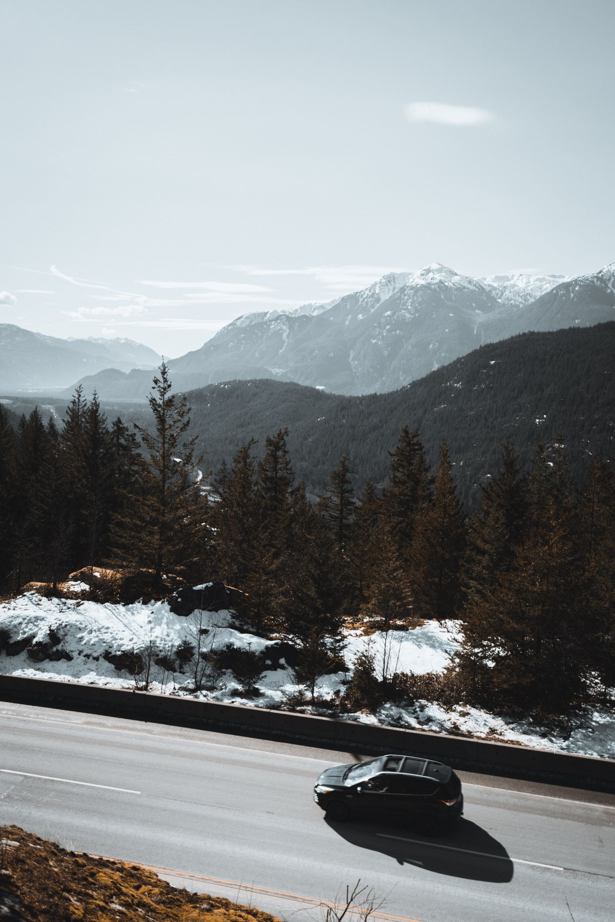 Route de montagne sinueuse en hiver avec sommets enneigés en arrière-plan