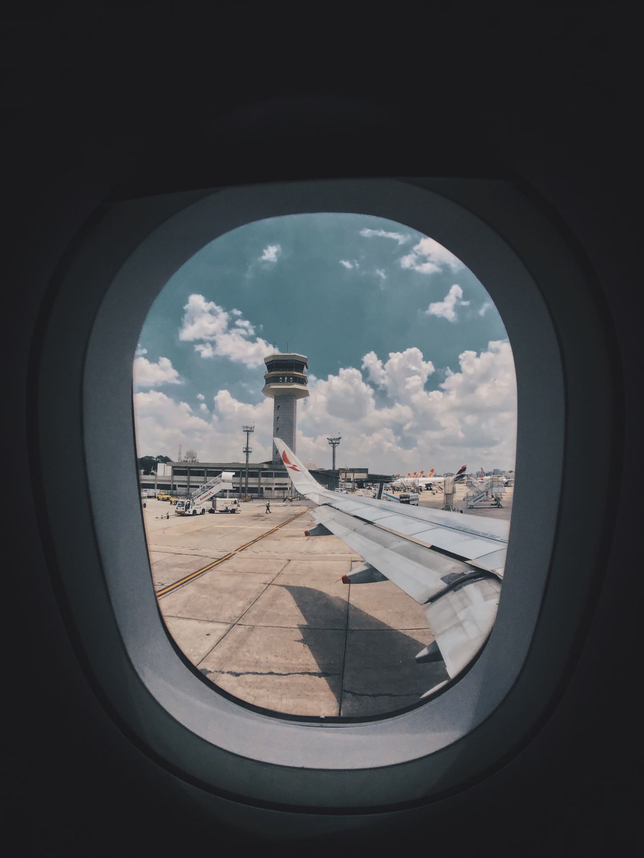 Vue depuis un hublot d'avion sur le tarmac et la tour de contrôle d'un aéroport