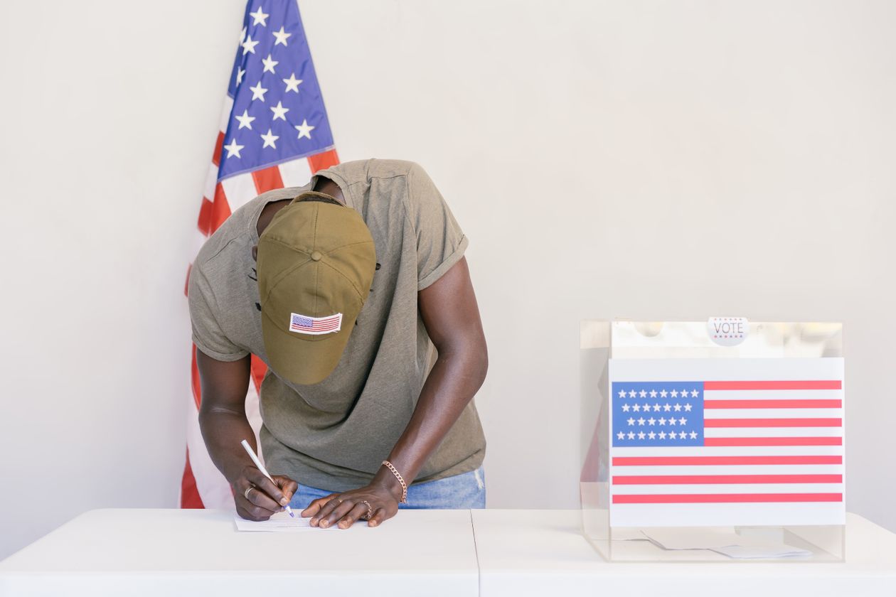 Homme remplissant son bulletin de vote dans un isoloir