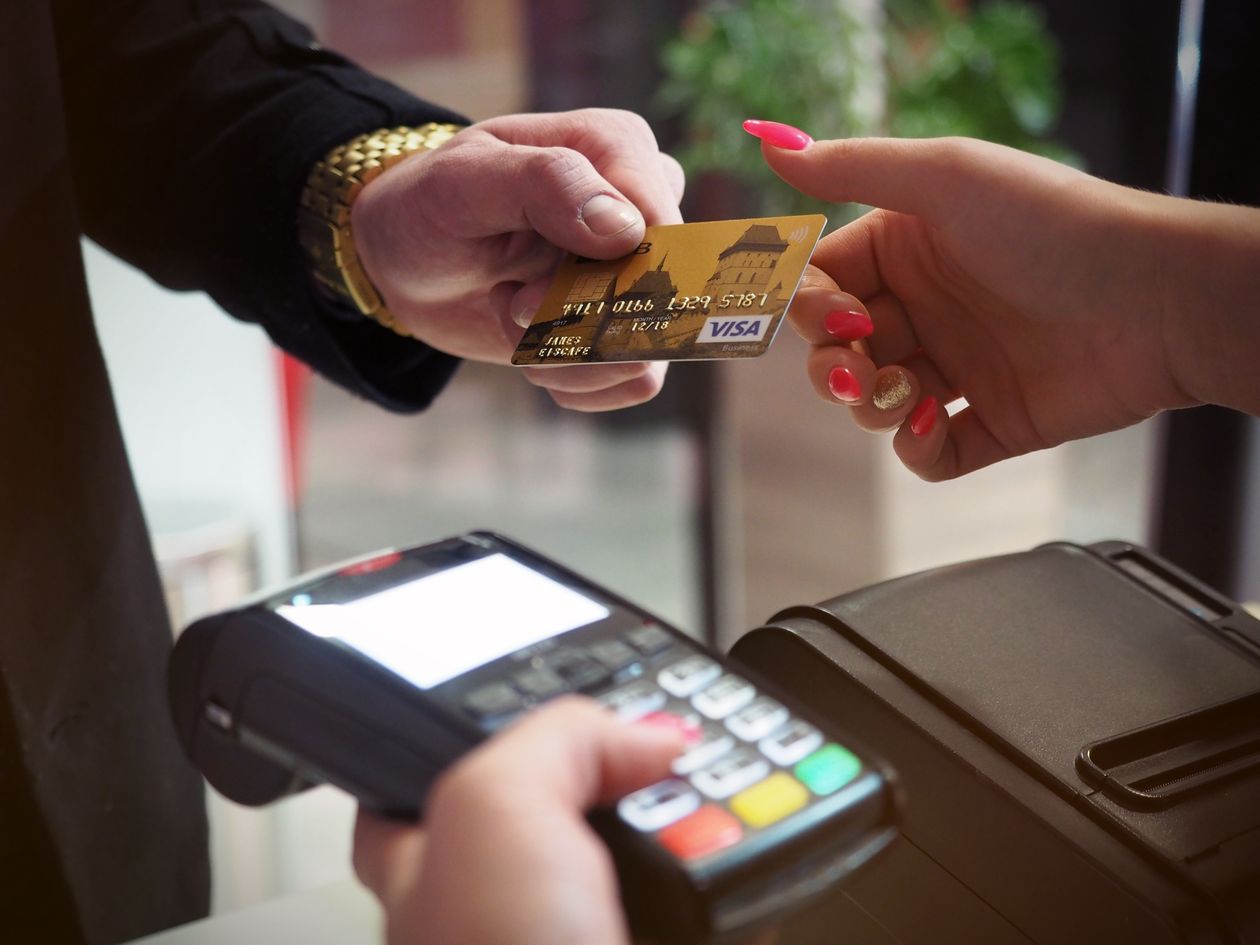 Main approchant une carte bancaire sans contact d'un terminal de paiement électronique