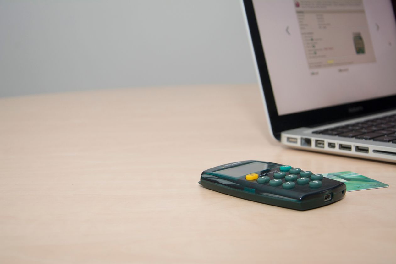 Calculatrice et carte bancaire à côté d'un ordinateur portable pour le paiement en ligne de la taxe foncière
