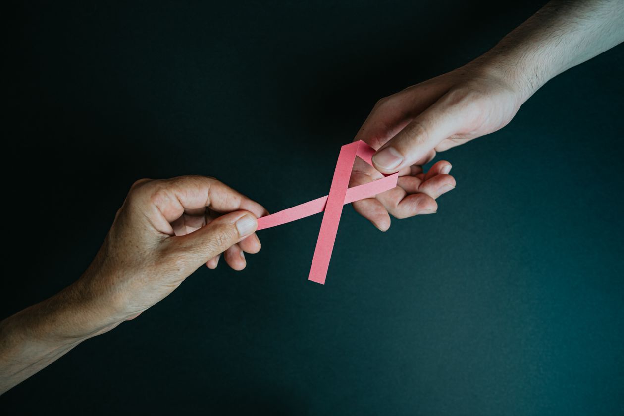 Deux mains échangeant un ruban rose symbolisant le soutien