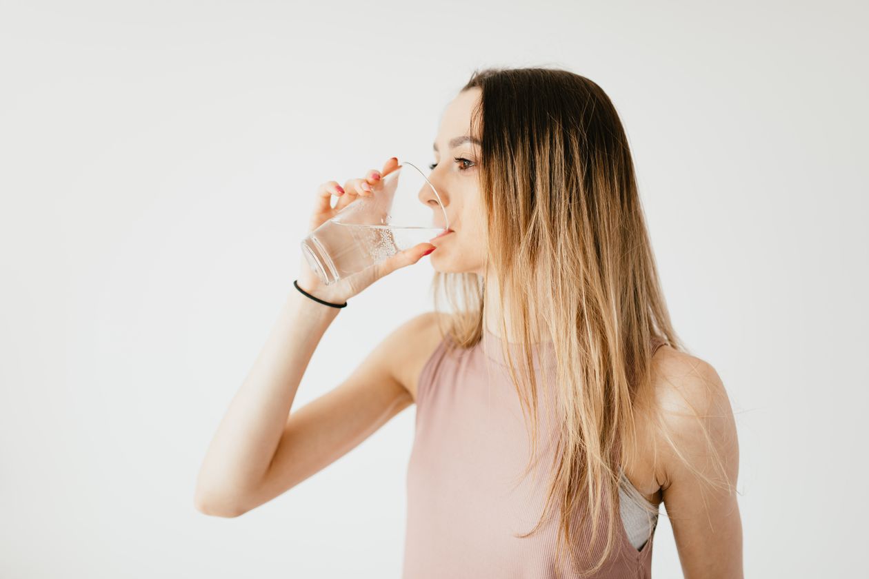 Jeune femme buvant un grand verre d'eau pour se réhydrater