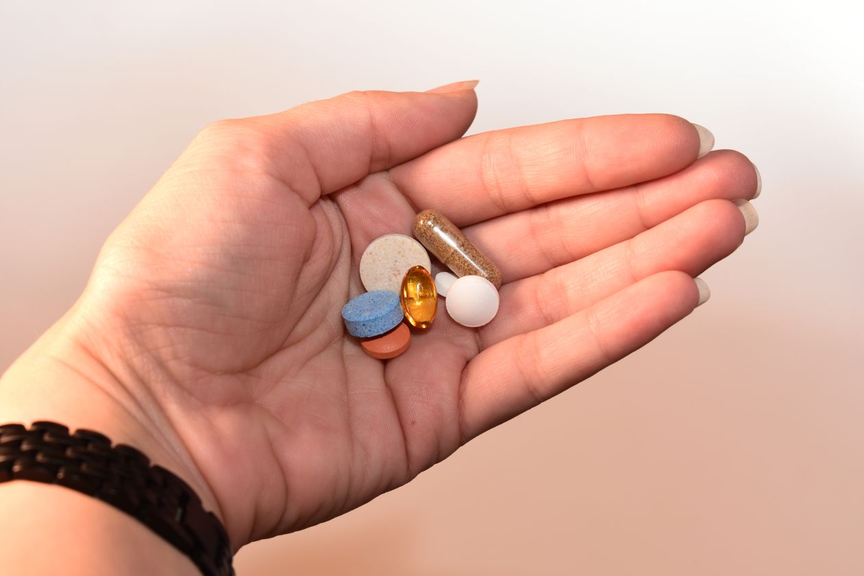 Personne tenant des comprimés et gélules dans la main, illustration des traitements antihistaminiques