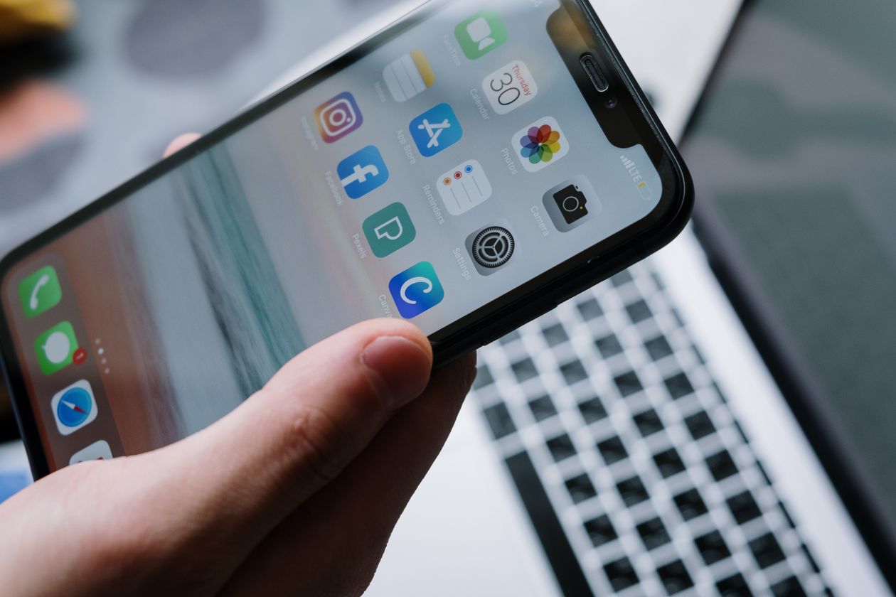 Personne configurant son smartphone à côté d'un ordinateur portable